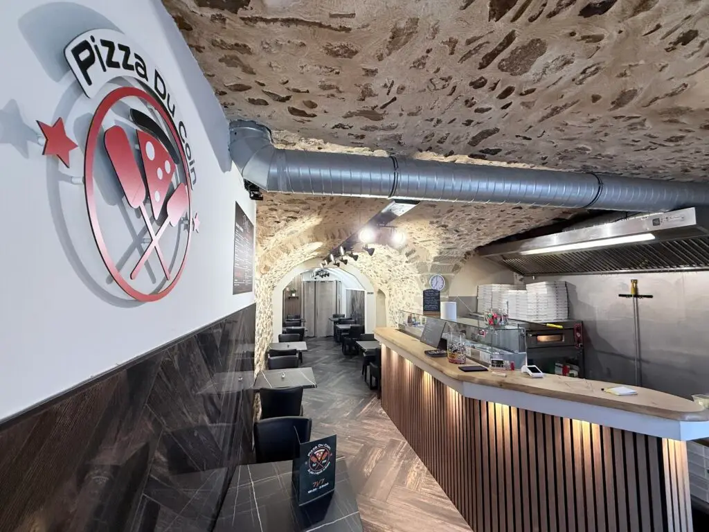 Intérieur chaleureux de la Pizzeria Crest – Pizza Du Coin, avec four à pizza et salle voûtée en pierre