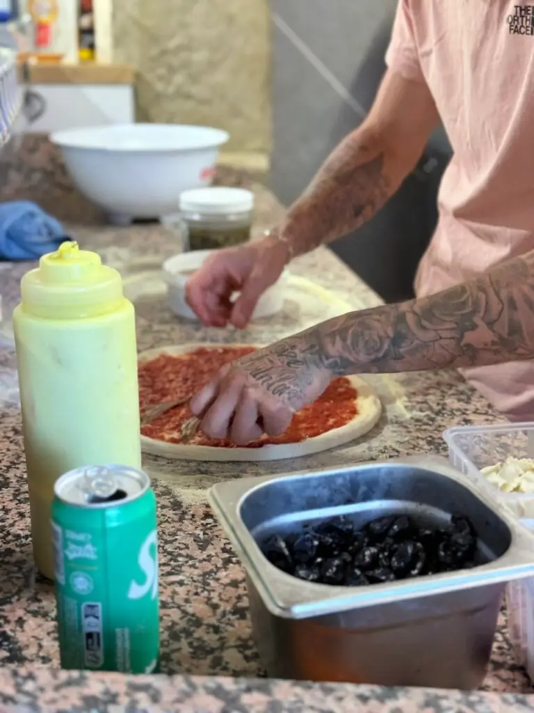 Préparation artisanale de pizza chez Pizza Du Coin à Crest – pâte garnie avec sauce tomate maison et ingrédients frais